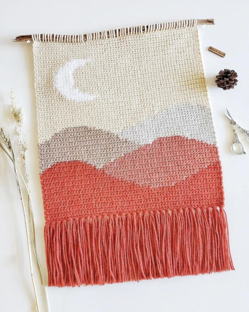 pink and white wall hanging with moon and hills