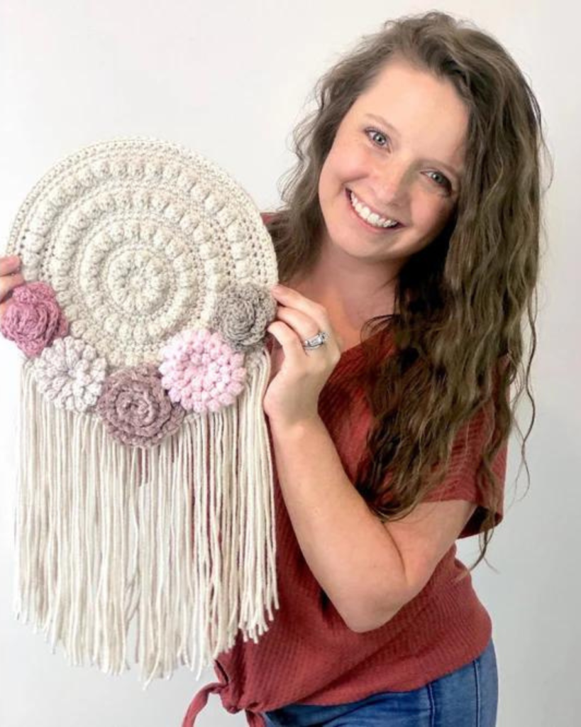 woman holding circular wall hanging with flowers