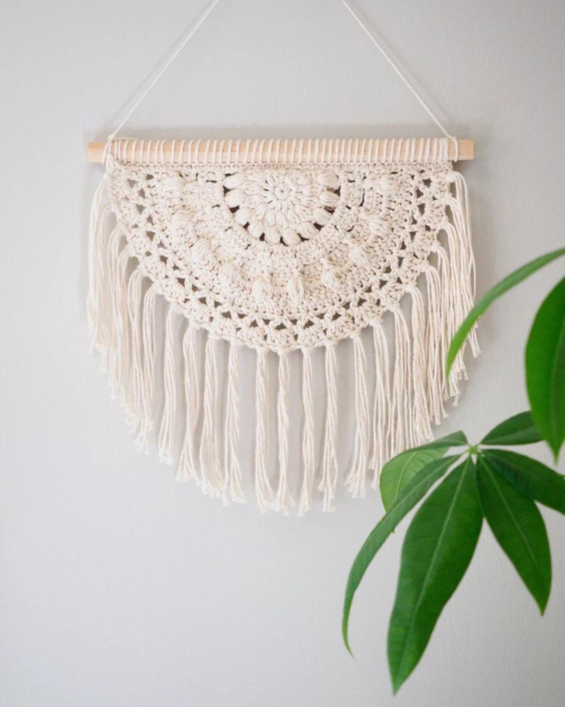 white half circle crochet wall hanging with plant