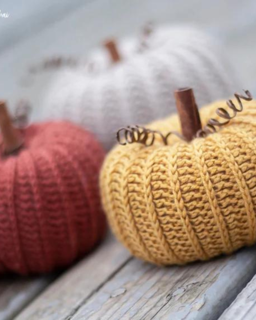 three crochet pumpkins in various colors and sizes