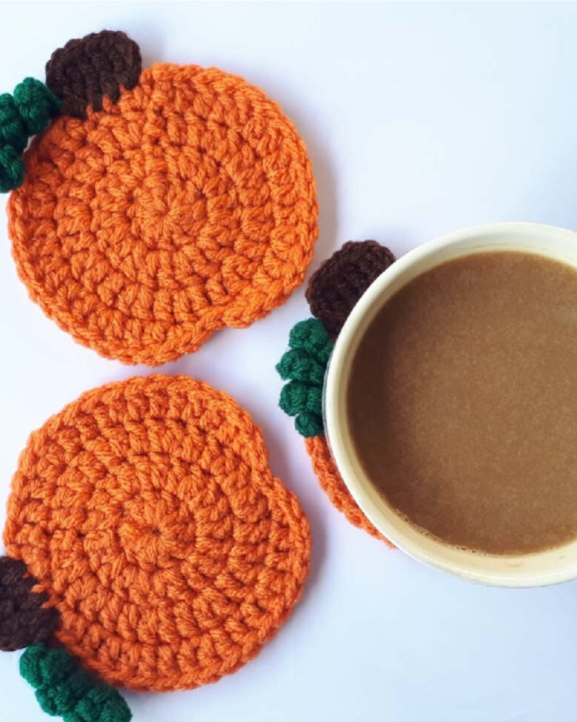 three crochet pumpkin coasters with coffee on top