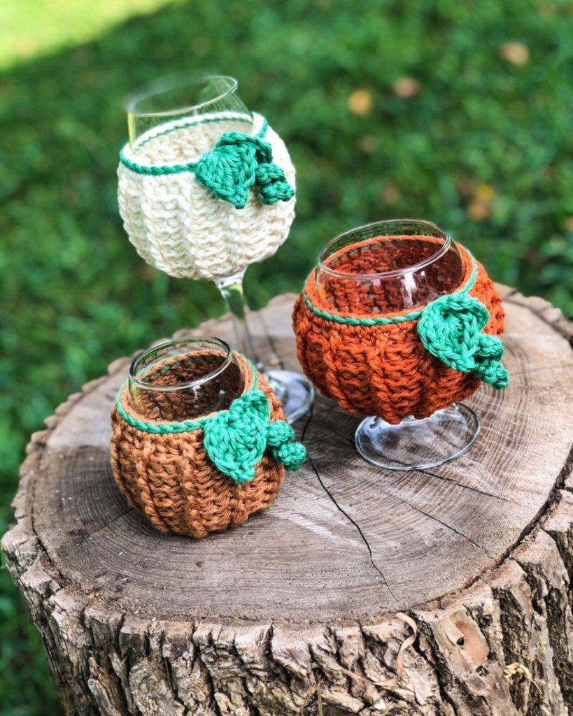 three crochet pumpkin cup cozies on a tree stump