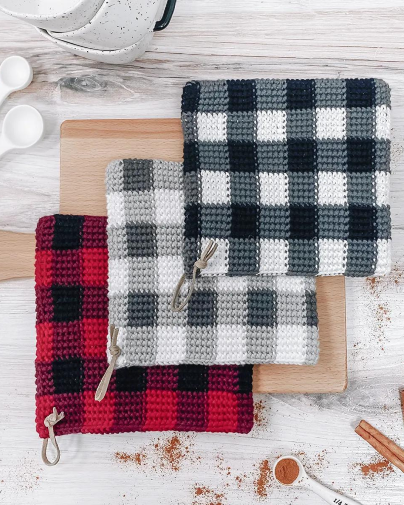 three plaid crochet potholders, one black and white, one grey and white, and one black and red