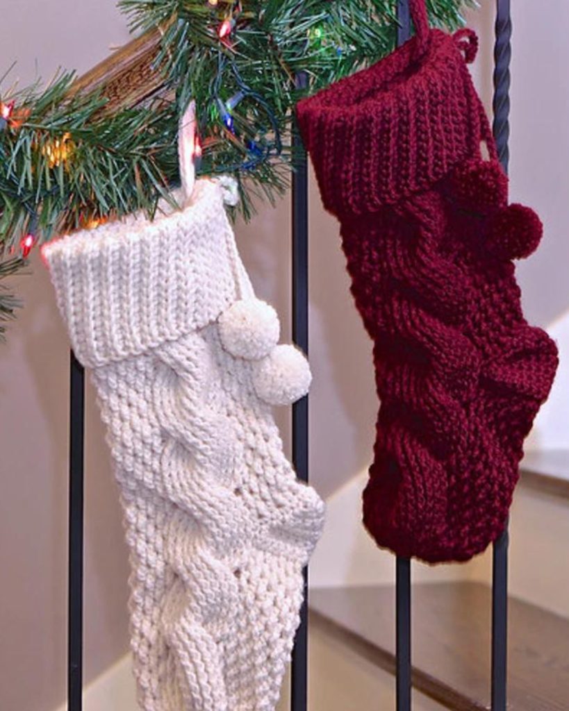 two crochet cable stitch christmas stockings, one white and one burgundy