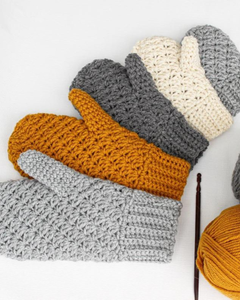 five crochet mittens in a variety of colors and sizes
