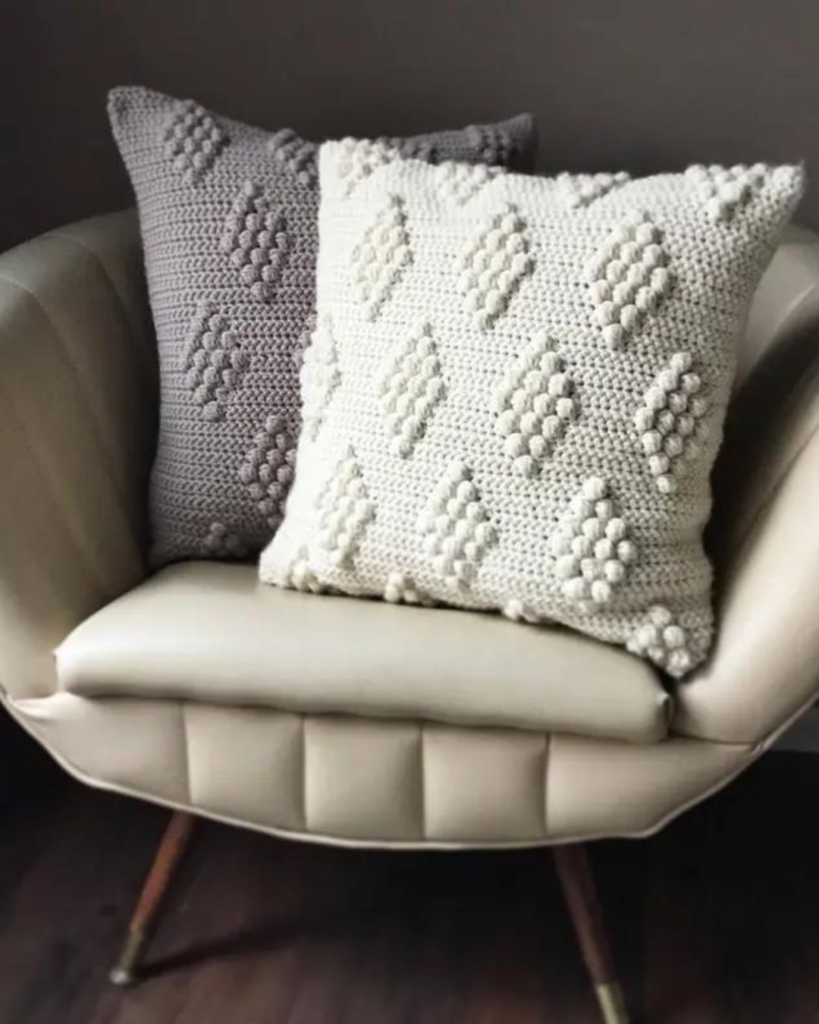 two crochet bobble stitch pillow covers, one grey and one white
