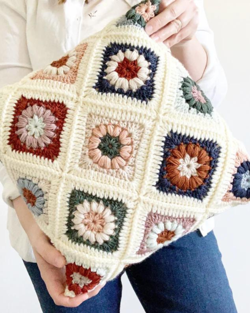 woman holding granny square pillow cover