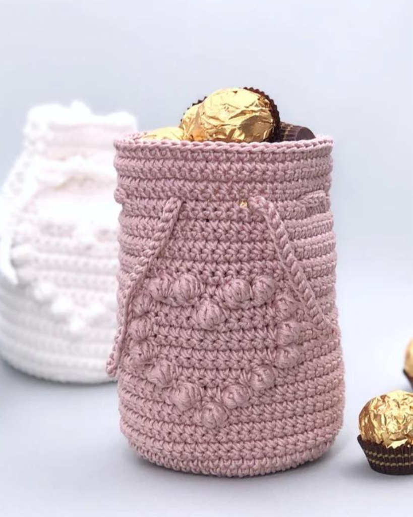 small pink crochet drawstring bag with bobble heart and chocolates inside