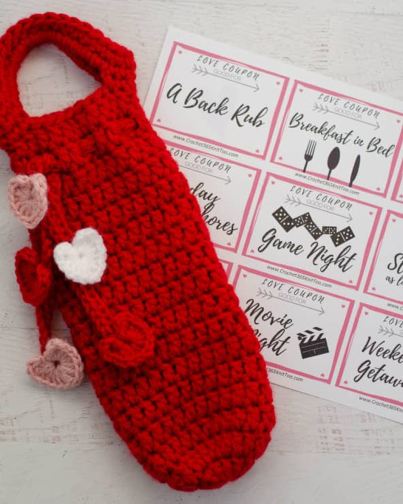 red crochet wine bottle holder with small hearts of various colors