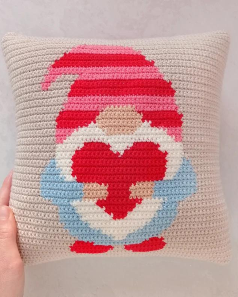 hand holding crochet pillow case with valentines day gnome holding a heart