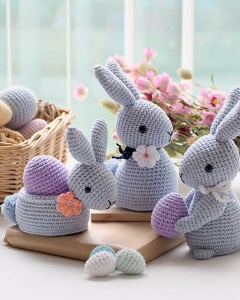 three grey crochet bunnies with multiple eggs