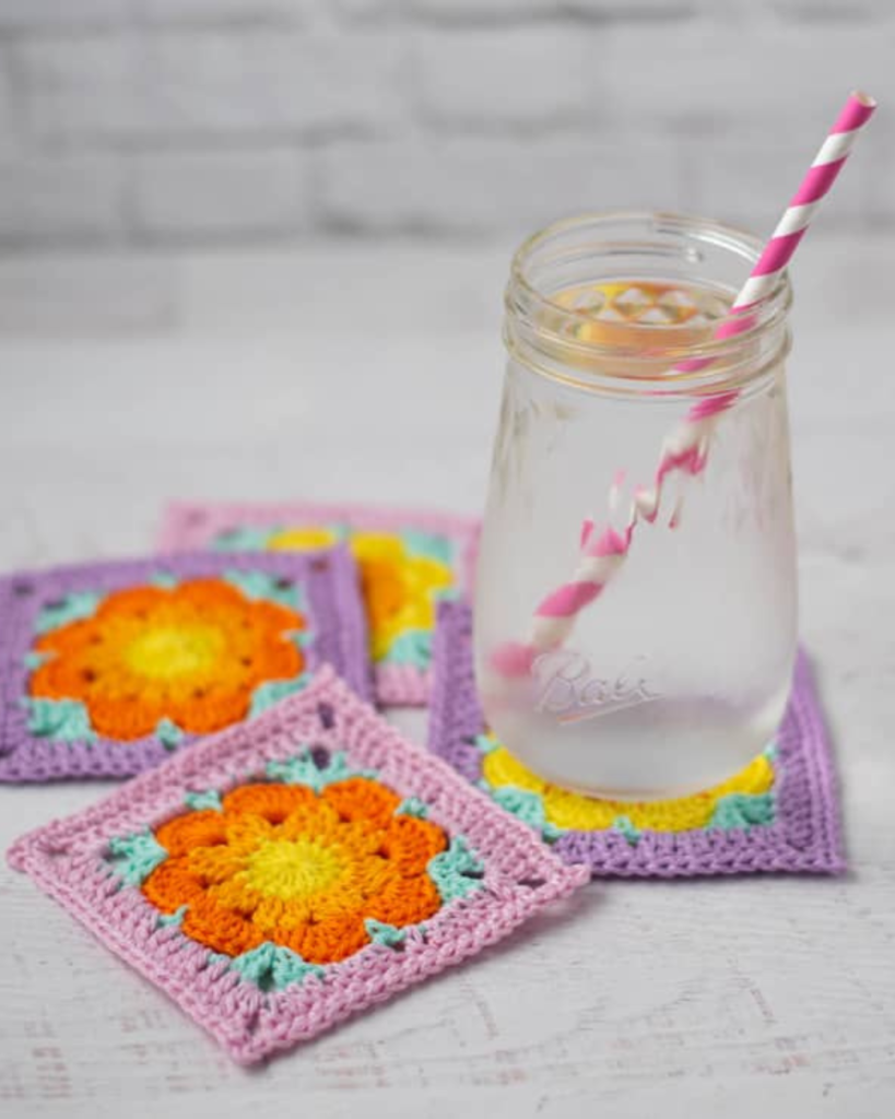 cup on top of pink and purple crochet coasters with orange and yellow flowers