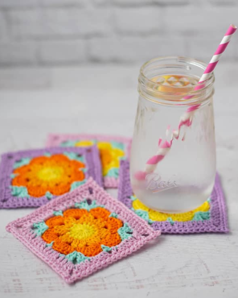 four pink, purple, and orange crochet flower square coasters