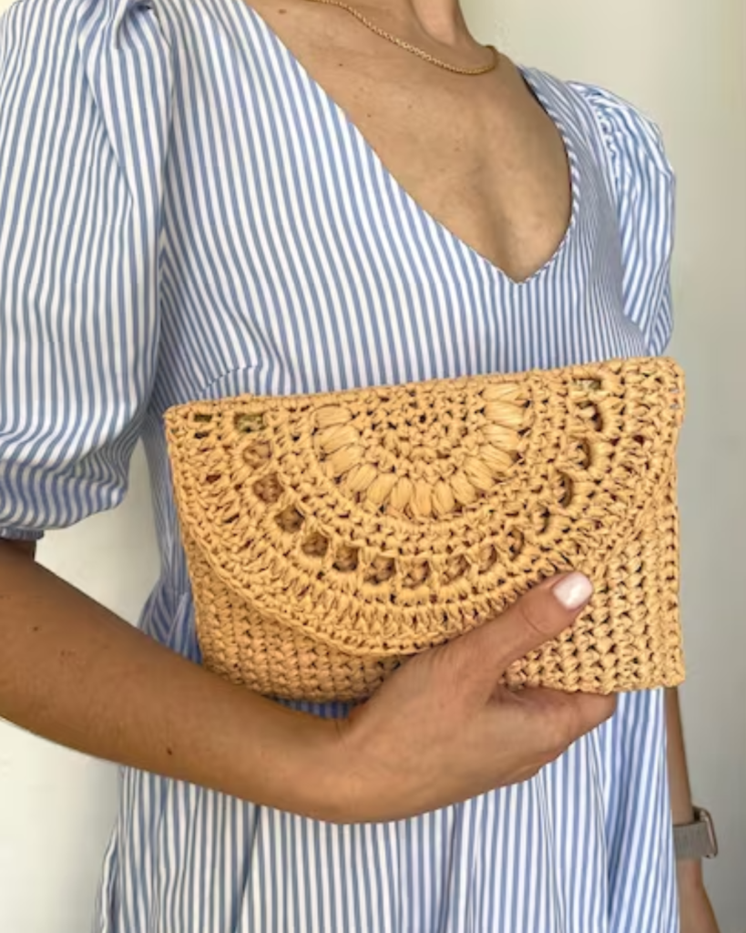 woman holding yellow crochet clutch bag