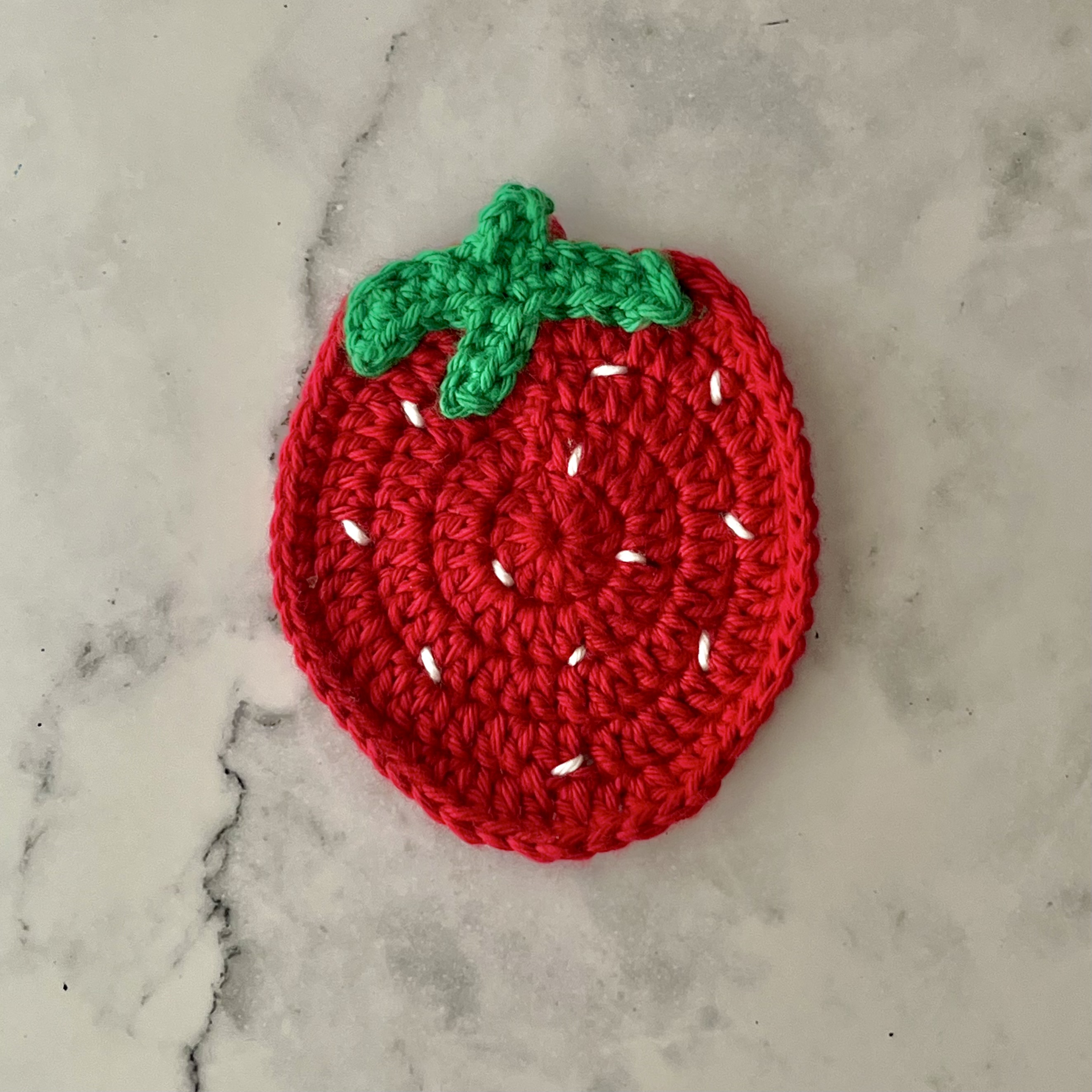 one red crochet strawberry coaster