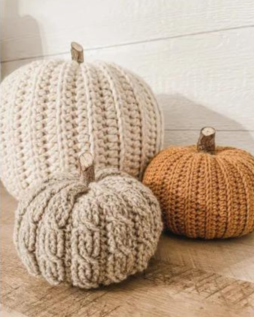 three crochet fall pumpkins of varying size, color, and texture