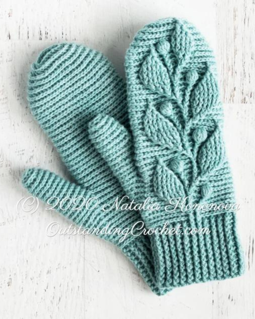 blue crochet mittens with elaborate plant design with cable stitch