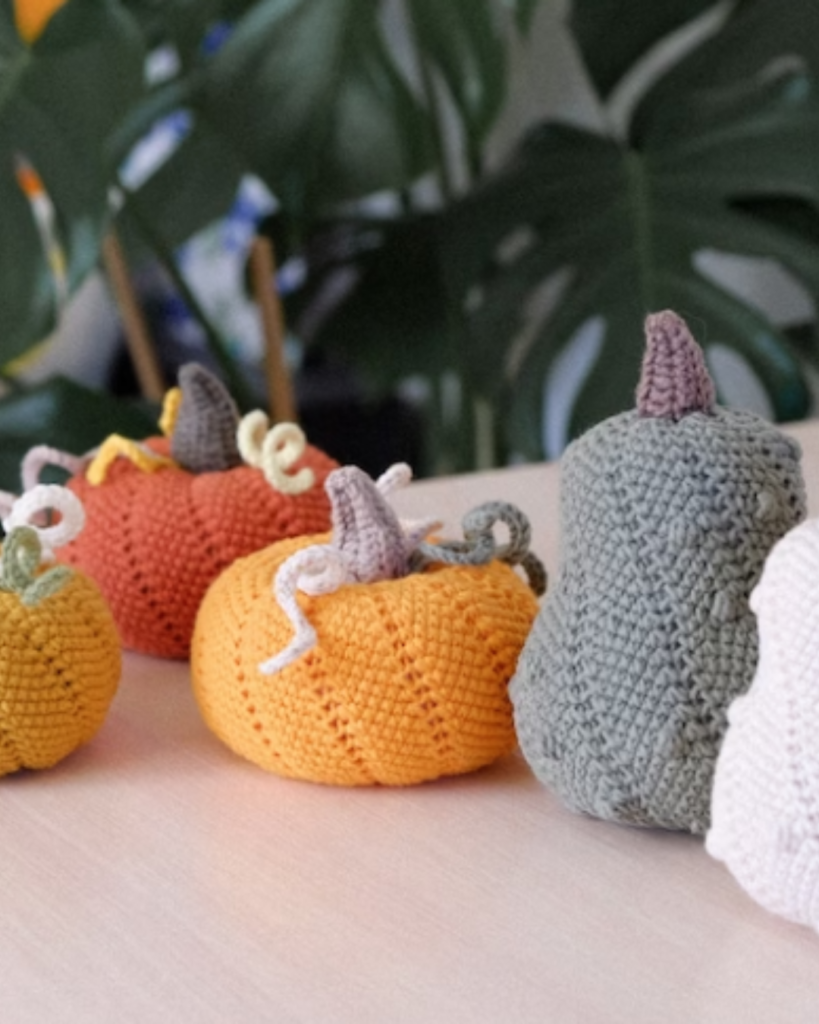 five crochet pumpkins of various size, shape, and color
