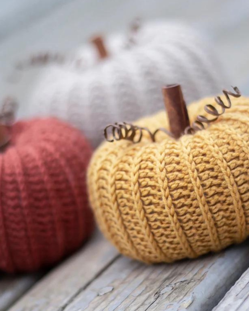 three crochet pumpkins of varying size and color