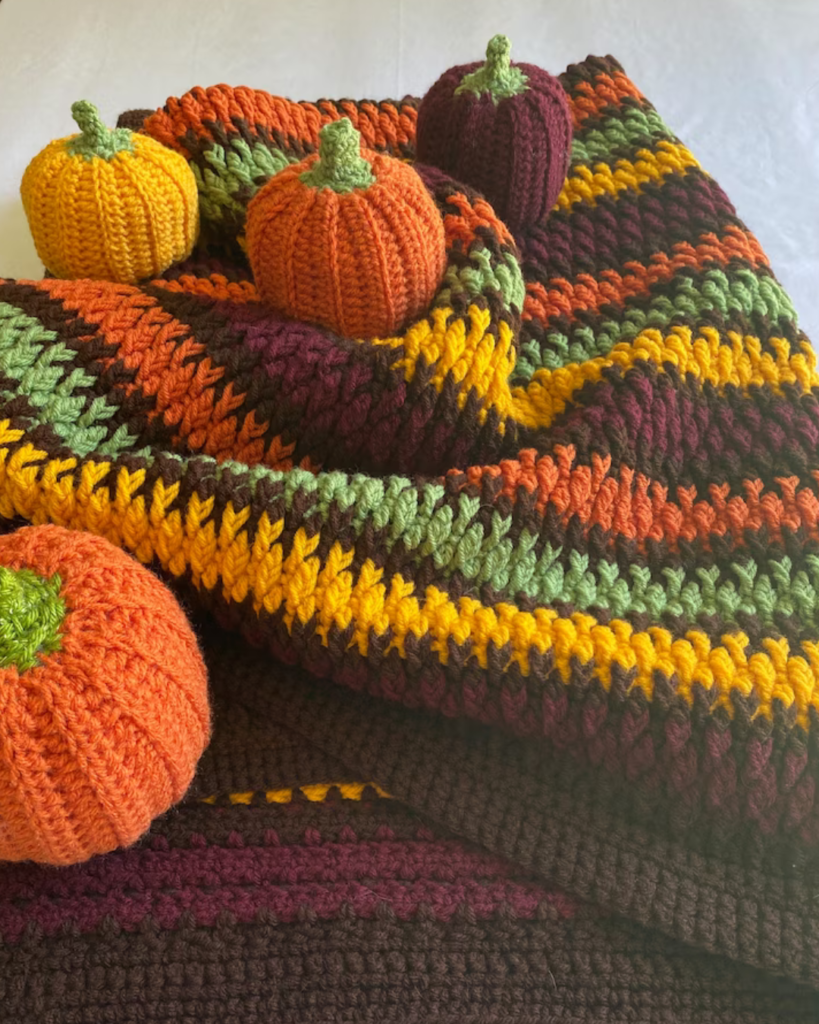 crochet multi-color alpine stitch stripe blanket with crochet amigurumi pumpkins
