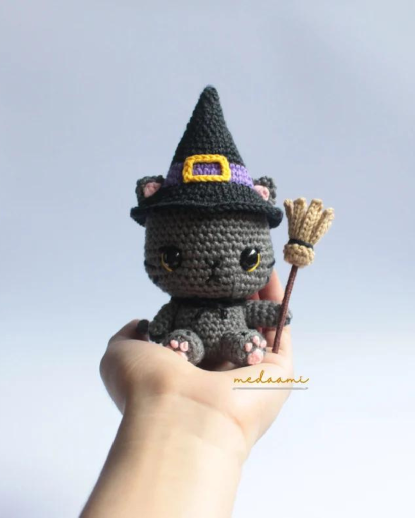 hand holding crochet cat witch