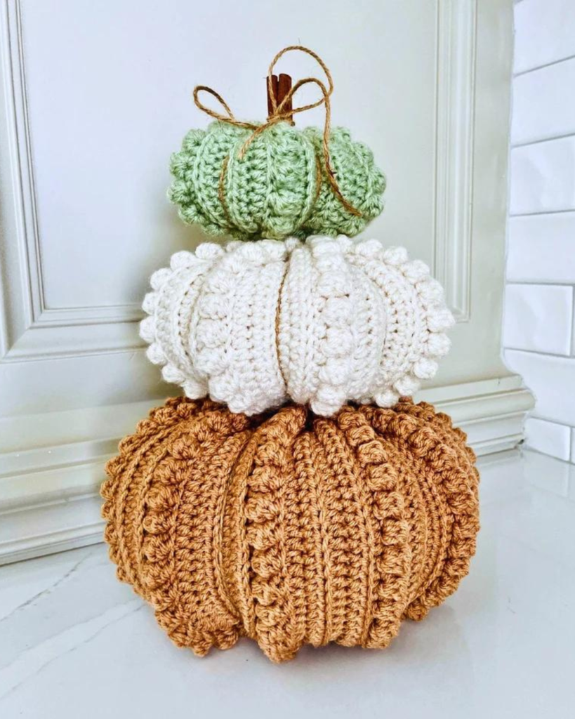 three crochet pumpkins of varying size and color