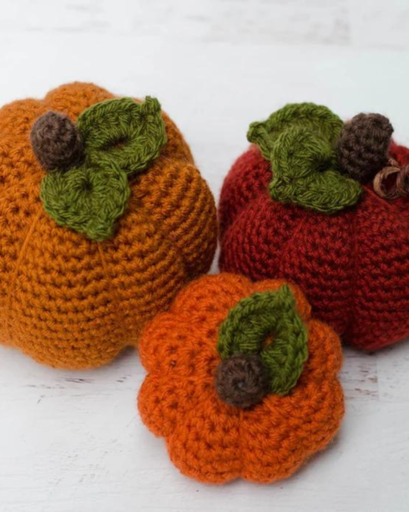 three crochet pumpkins of varying size and color