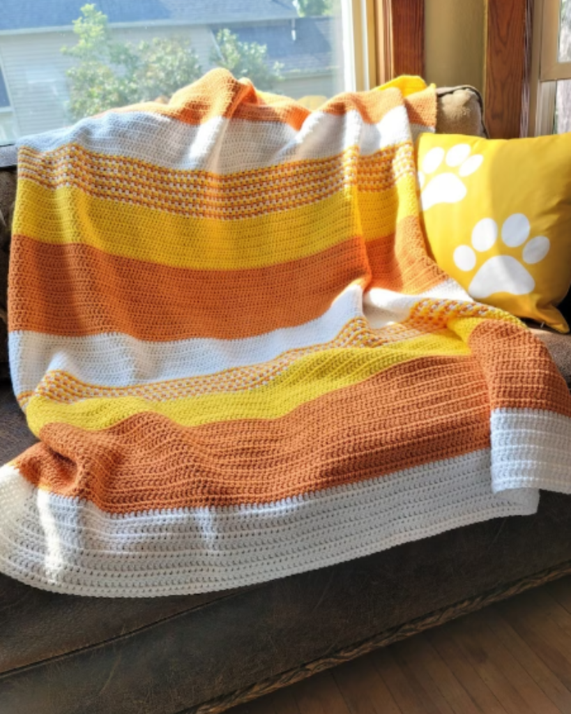 white, yellow, and orange striped crochet halloween decor blanket