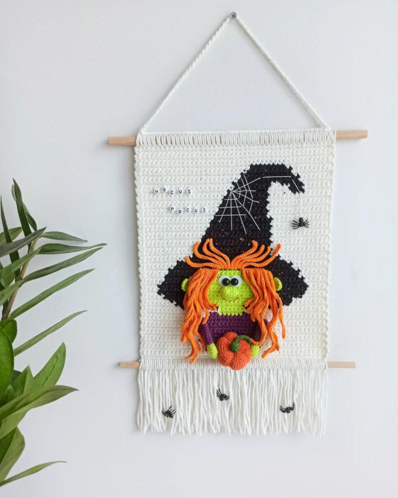 white wallhanging with witch holding a pumpkin