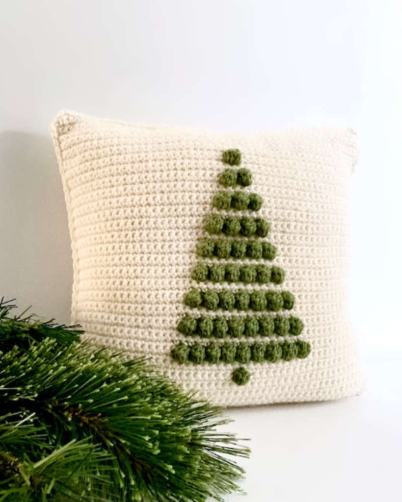 square white crochet pillow with one green bobble tree