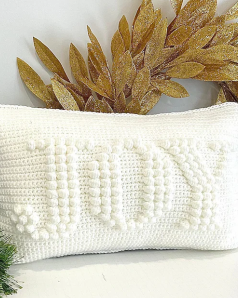 white pillow with bobble stitch spelling the word "JOY"