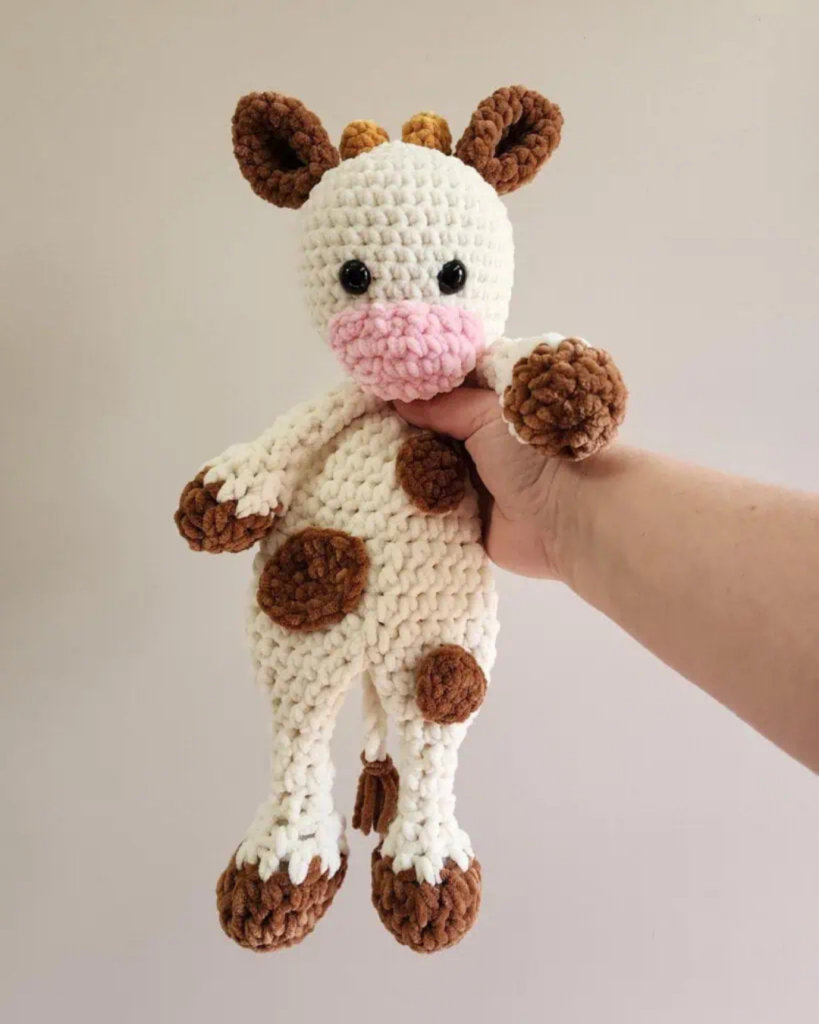 hand holding cow crochet snuggler