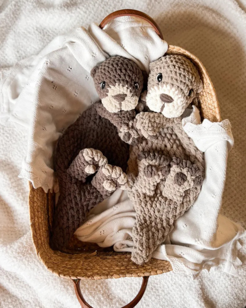 two crochet snuggler otters in a basket