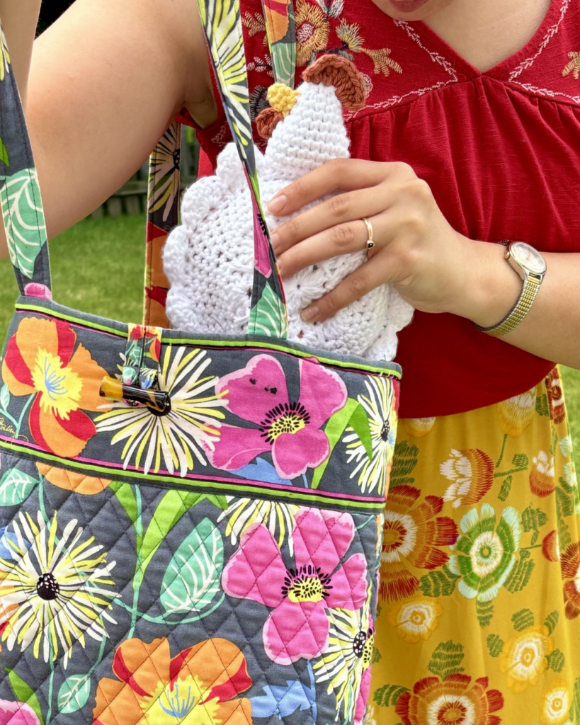 woman putting crochet chicken in colorful floral bag