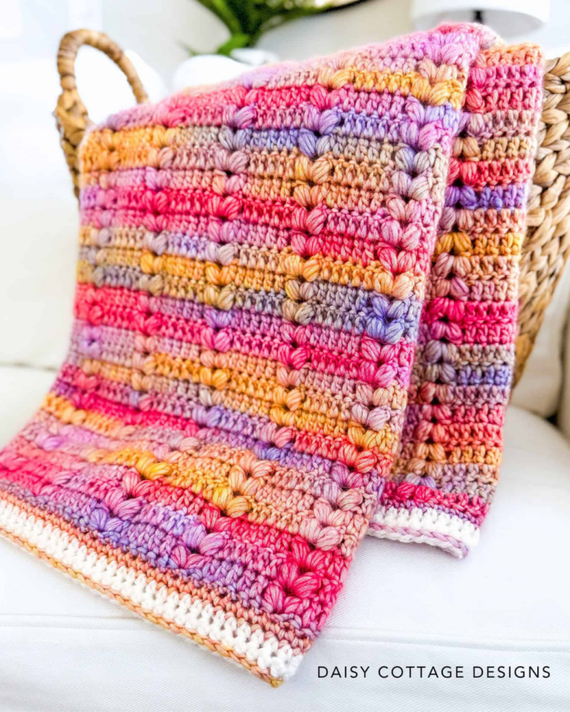 handmade crochet baby blanket draped over basket