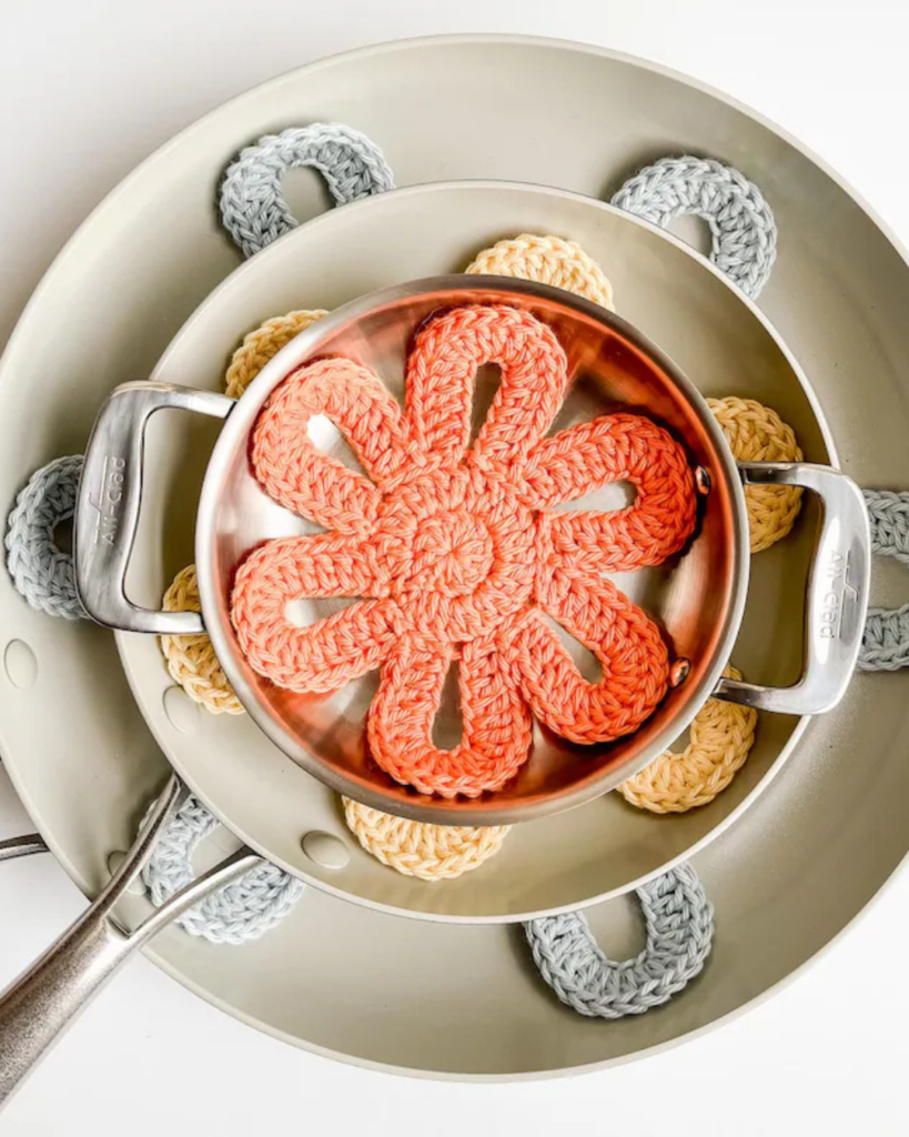 Stack of flower-shaped crochet pan protectors placed between cookware