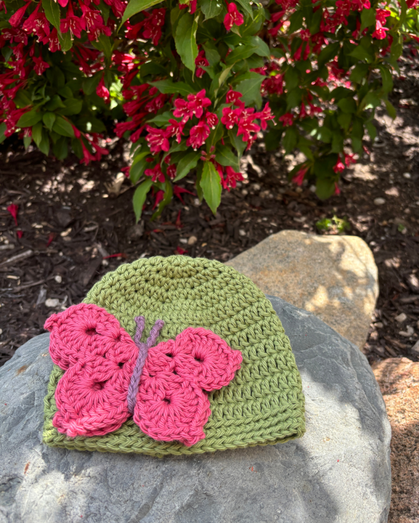 Close-up of Butterfly Kisses crochet baby hat with colorful butterfly applique