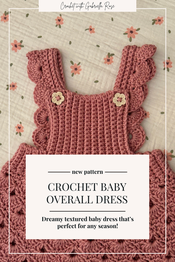 Front view of the Storybook Lane crochet baby overall dress showing the shell stitch skirt, ribbed bib, and wooden button straps.