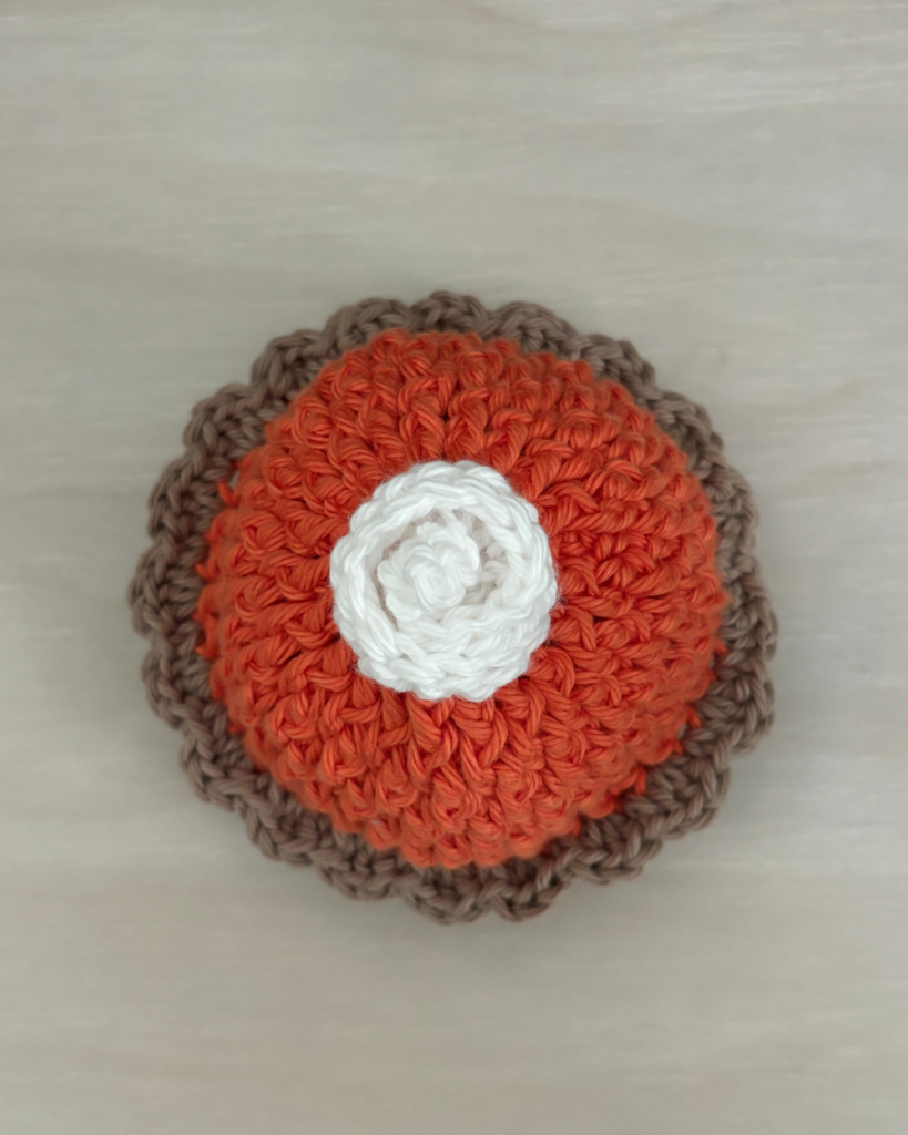 Top view of the crochet Pumpkin Pie Baby Hat with a white whipped cream dollop on top
