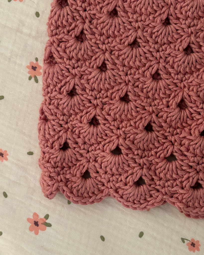 Close-up of the shell stitch skirt on a handmade crochet baby overall dress.