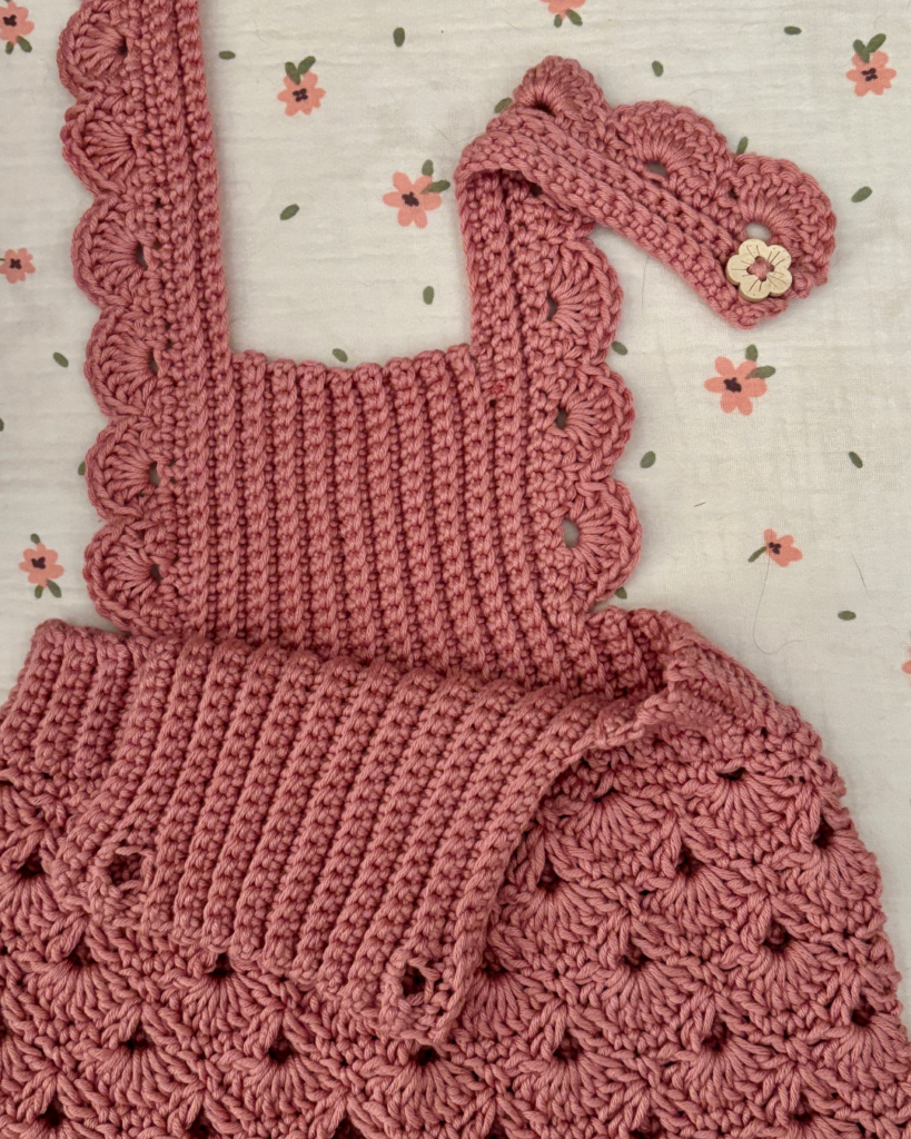 Close-up of the shell stitch skirt on a handmade crochet baby overall dress.