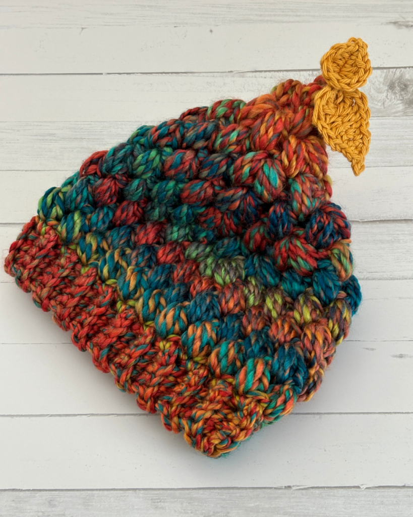 Side view of the Woodland Wanderer toddler hat showing the textured puff stitches and dangling leaves