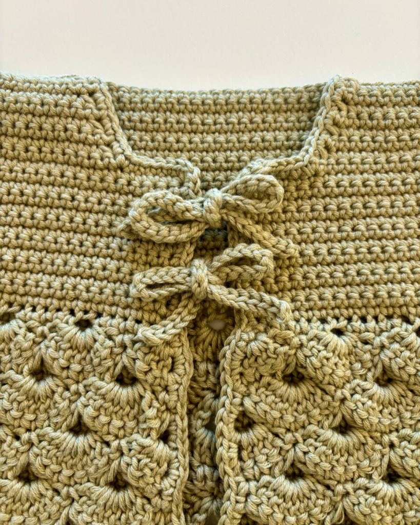 Close-up of the two bows tying the front of the crochet baby cardigan
