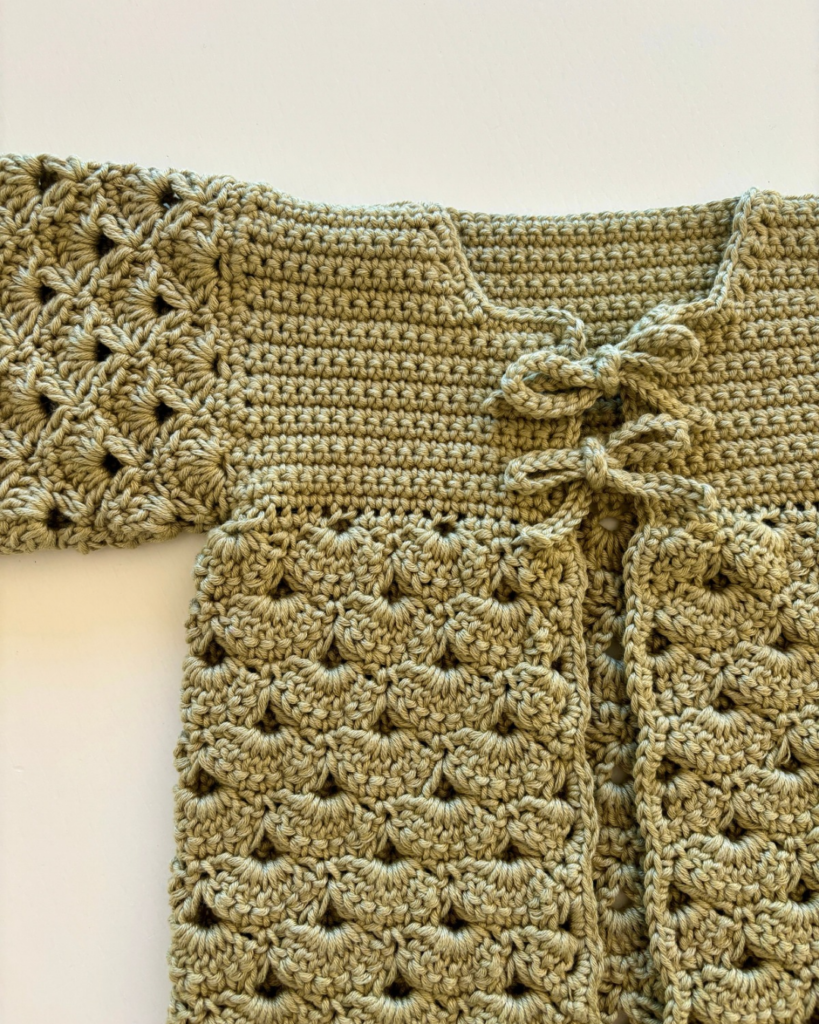 Close-up of the two bows tying the front of the crochet baby cardigan