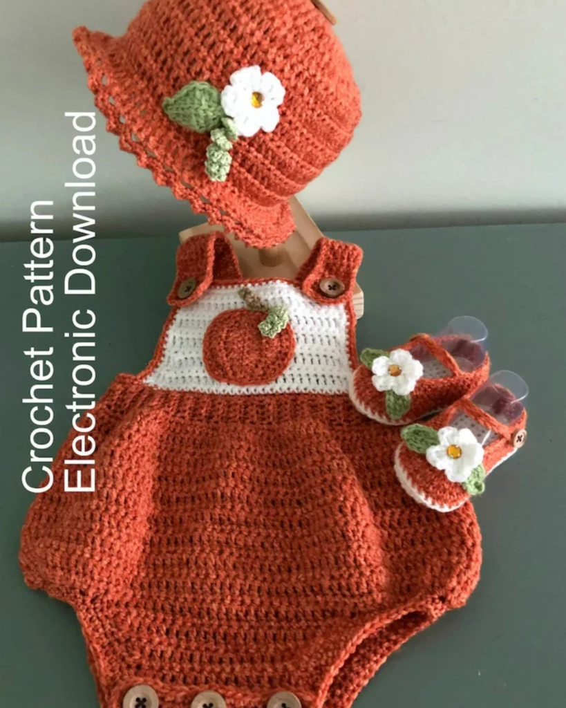 Crochet baby pumpkin romper set with an orange flowered bucket hat, pumpkin applique, and matching floral sandals.