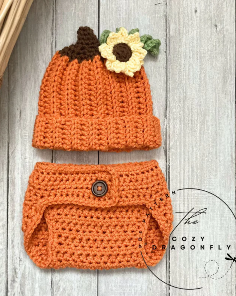 Crochet baby pumpkin outfit with orange bloomers and a pumpkin hat topped with a sunflower.