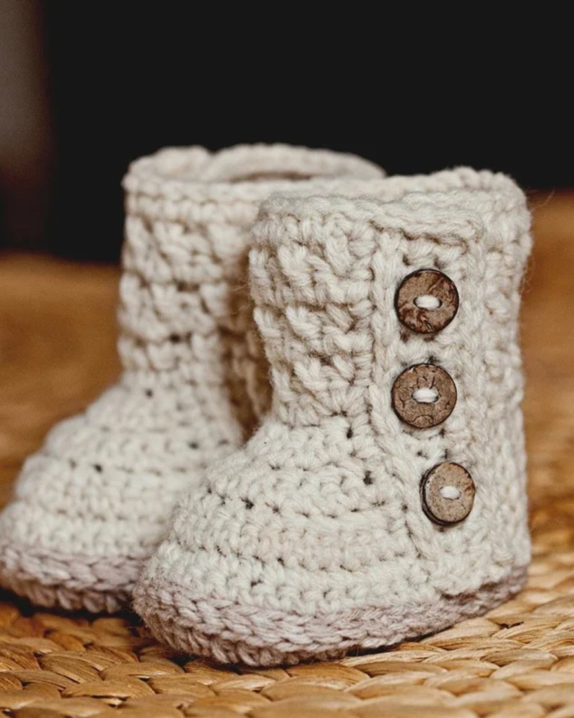 Crochet baby boots with a cozy design and three decorative buttons along each side.