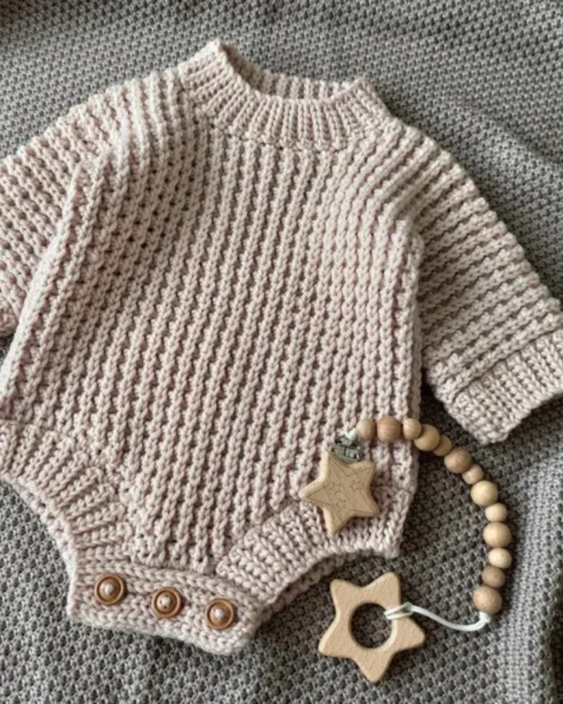 Crochet baby romper with long sleeves and a classic knit-style textured stitch pattern.